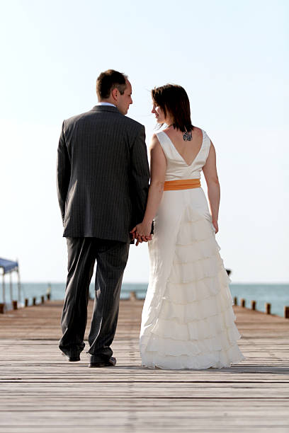 o noivo e a noiva de retrato de beleza no píer na praia ensolarada - eternity wedding beach human hand - fotografias e filmes do acervo