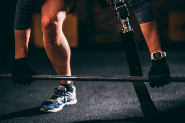 istock Adaptive male athlete with a leg prosthetic doing a dead-lifting exercise with a barbell in a gym gym 1127979368