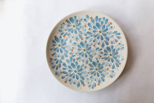 a white round plate with floral and line pattern on white background