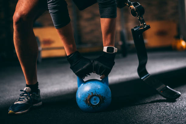 istock Adaptive athlete with a prosthetic leg doing a gym exercise with a kettlebell in a gym 1127979616