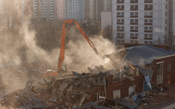 istock Excavator demolition dismantles the building in sunlit dust cloud 1127981257