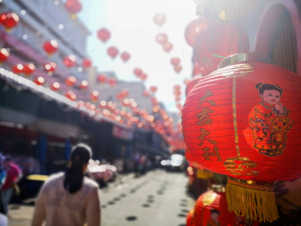 Colorful Chinese New Year red and gold traditional festival lanterns adorn part of the famous traditional Chiang Mai Worawot Market near the river in downtown Chiang Mai, whilst tourists and locals pass through the street admiring the decorations. colorido el año nuevo chino rojo y oro tradicional festival linternas adornan parte del famoso chiang mai worawot mercado tradicional cerca del río en el centro de chiang mai, mientras que los turistas y los lugareños pasan por la calle admirando la dec
