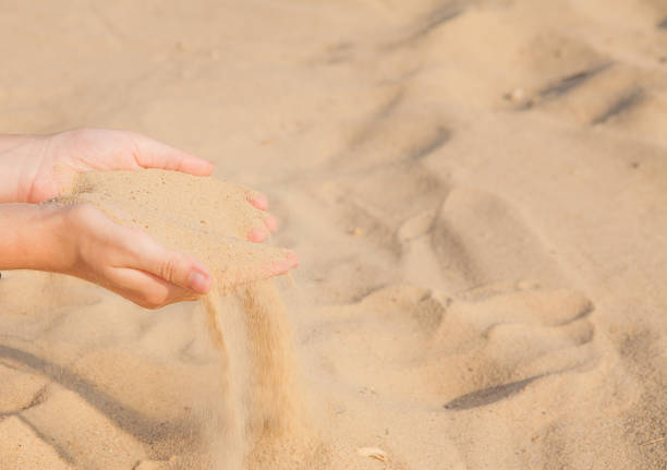 istock Sand flowing through the woman's hands on the beach 1127994910