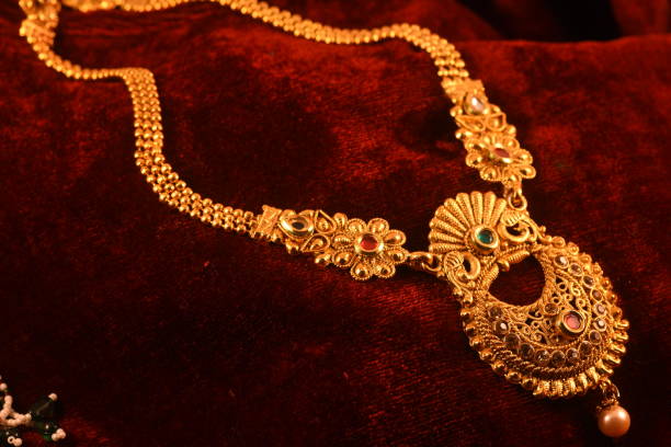istock Designer beautiful golden necklace closeup macro image on red background. 1127995804