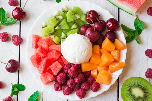 fresh mixed fruit served on white plate with ice cream