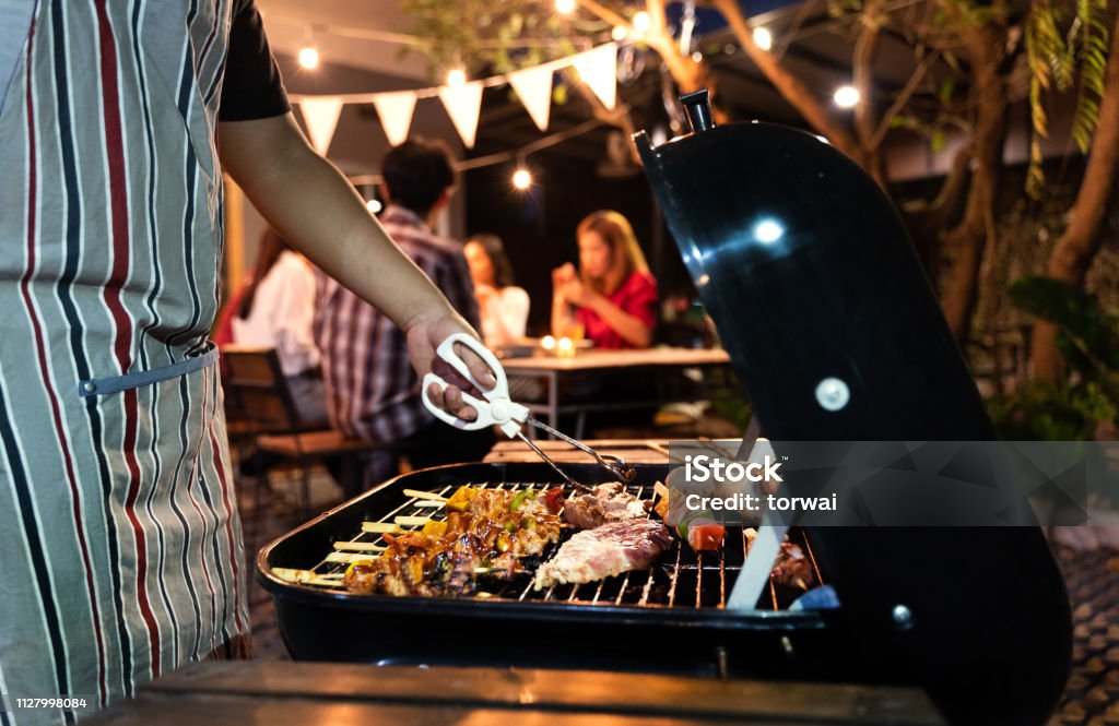 Asiatischer Mann sind für eine Gruppe von Freunden zu Grillen Essen kochen - Lizenzfrei Gartengrill Stock-Foto