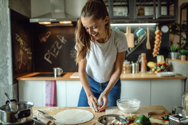 Woman preparing dought for pizza Woman in kitchen preparing dough for pizza flour mess stock pictures, royalty-free photos & images