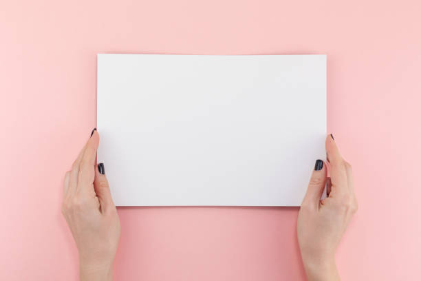 istock Woman hands with blank A4 paper sheet mockup 1127999612
