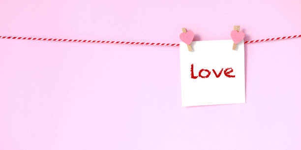 istock Love word on white paper notepad hanging on pink background, with copy space for text, Valentine's day greeting card 1128000985