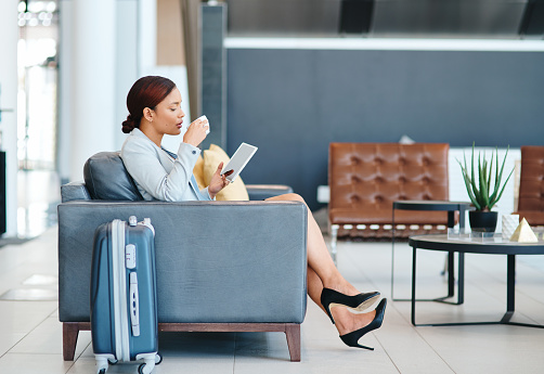 Full length shot of an attractive young businesswoman using her tablet while sitting in the airport