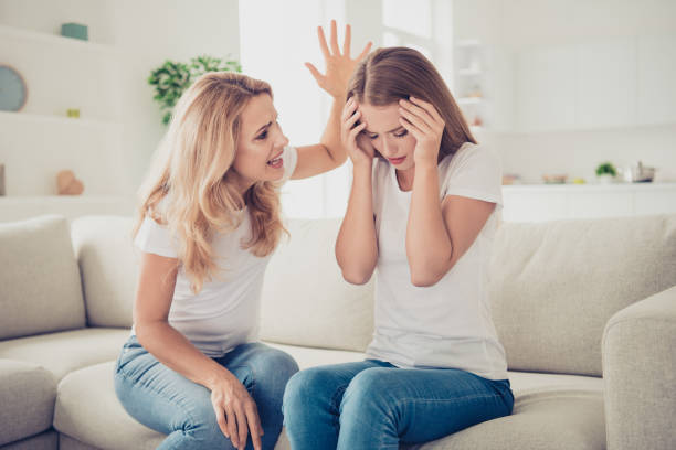 istock Two nice attractive charming blonde ladies sitting on divan mad mom mum having fight with lazy schoolgirl in modern light white interior room house indoors 1128001321