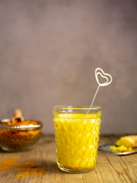golden milk with turmeric in a drinking glass - herzform imagens e fotografias de stock