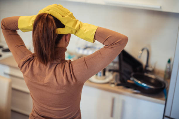 istock Stressed housewife looking at dirty dishes 1128004447