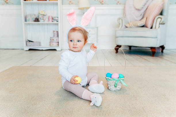 istock Little child girl wearing bunny ears on Easter day and playing with painted eggs 1128009862