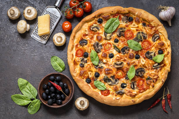 istock pizza with tomatoes, cheese, mushrooms and spinach on a dark background 1128010045