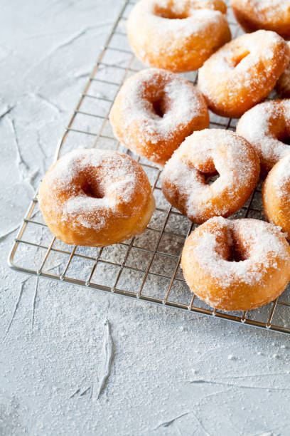 istock Bunch Of Donuts With Powdered Sugar On A Cooling Tray 1128012066