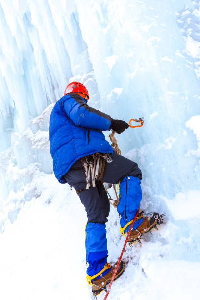 Photo of ice climber checks the reliability of the anchor