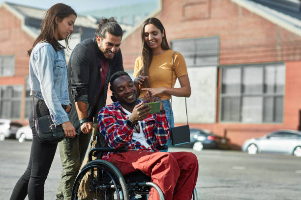 istock Friends watching photos on phone with disabled man 1128016350
