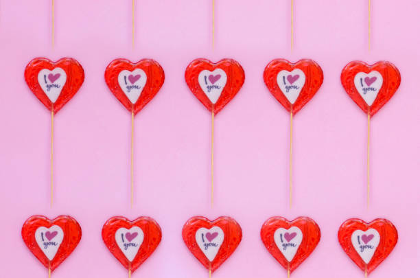 istock Red lollypop heart shape candy on stick on pink background 1128016976