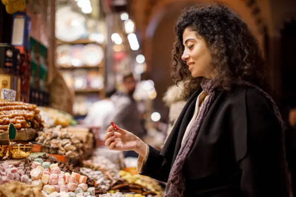 Young woman shopping in turkish delight shop in Grand Bazaar, Istanbul, Turkey