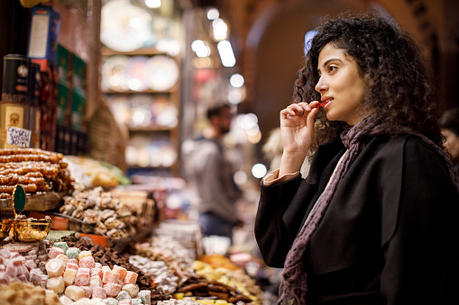 Young woman shopping in turkish delight shop in Grand Bazaar, Istanbul, Turkey