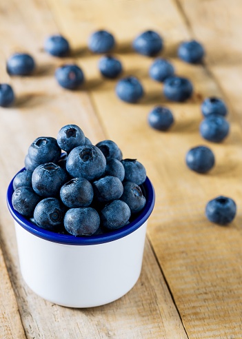 Pile of blueberries in the white cup on wood table fresh fruit background close up picture