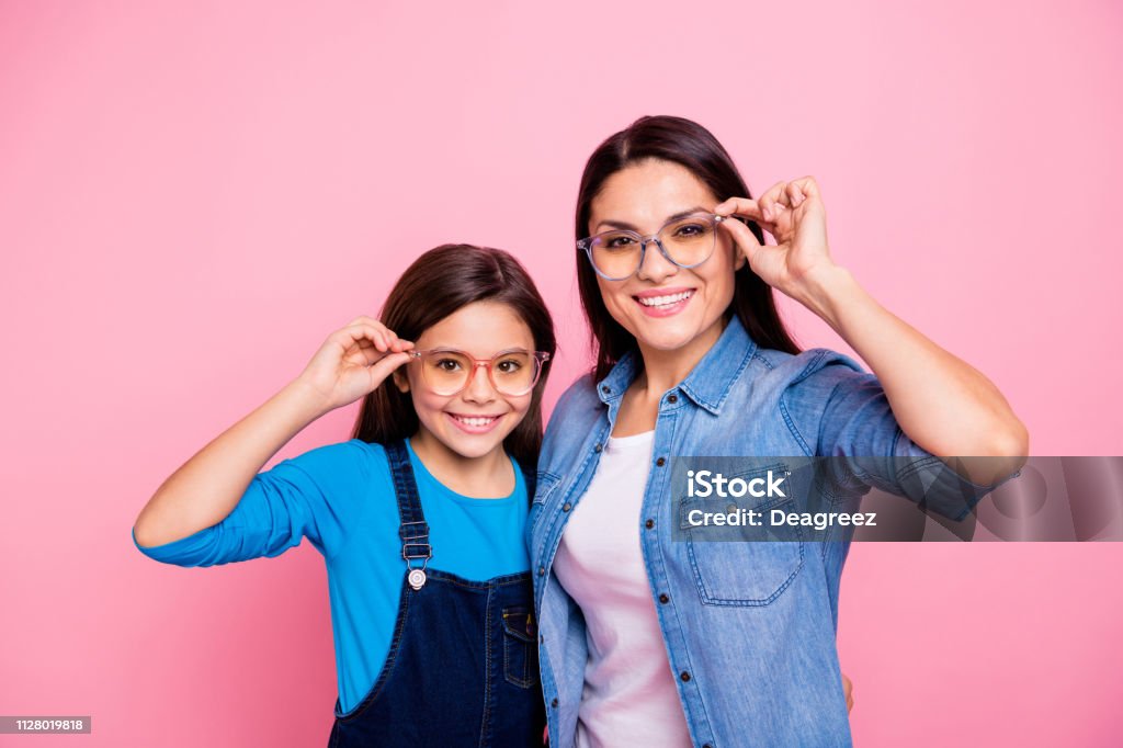 Portrait of two nice trendy cute winsome pretty lovely attractive charming cheerful cheery positive straight-haired girls touching glasses lifestyle isolated over pink pastel background Eyeglasses Stock Photo