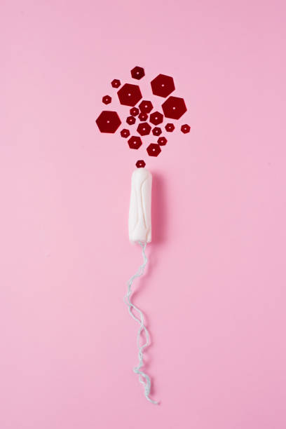 menstrual tampon with red glitter over pink background. Woman, reproductive health gynecology stock photo