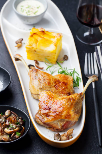 Duck legs confit with potato gratin and mushroom. Restaurant serving. Copy space. Top view. Duck legs confit with potato gratin and mushroom. Restaurant serving. Copy space. Top view confit stock pictures, royalty-free photos & images