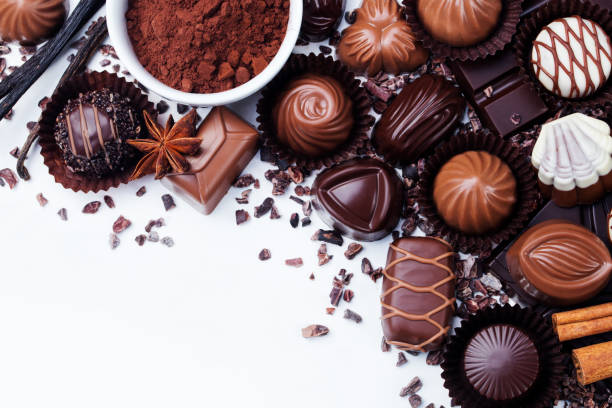 assortimento di caramelle al cioccolato, prodotti a base di cacao e spezie su sfondo bianco. vista dall'alto. spazio di copia - truffle chocolate candy chocolate candy foto e immagini stock