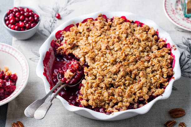 cranberry crumble, knackig in eine auflaufform legen. grau hinterlegt. hautnah. - cranberry stock-fotos und bilder