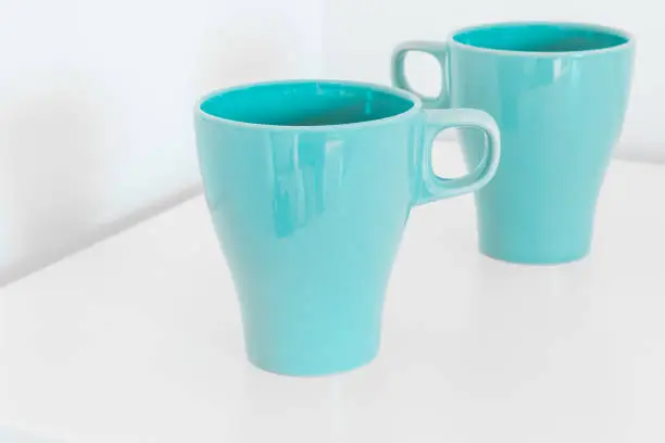 Two blue breakfast cups on a white table