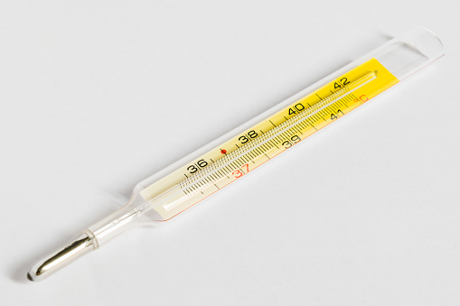 Un termómetro de mercurio tradicional sobre un fondo blanco photo