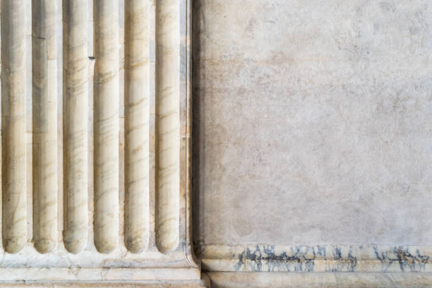 An ancient marble column with a portion of stone wall stock photo