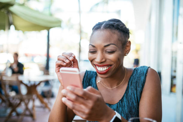Beautiful millennial Afro-Latino woman using mobile phone and sharing content on social media Hispanic woman using smart phone for talking and communication in USA afro latinx ethnicity stock pictures, royalty-free photos & images