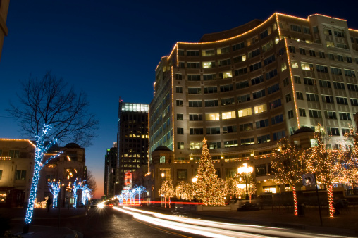 A street is decorated with Christmas lights. A slow exposure creates streaks of light from passing cars. Reston, Viriginia, Christmas