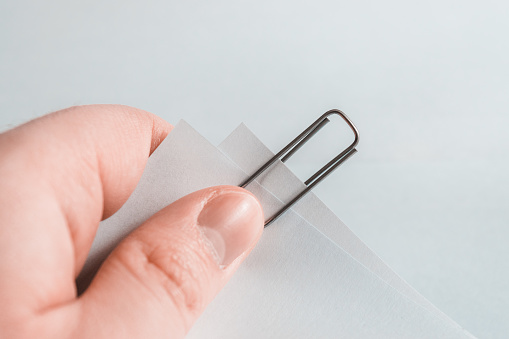 Mano de un empleado pide hojas de papel de documentos con un clip metálico photo