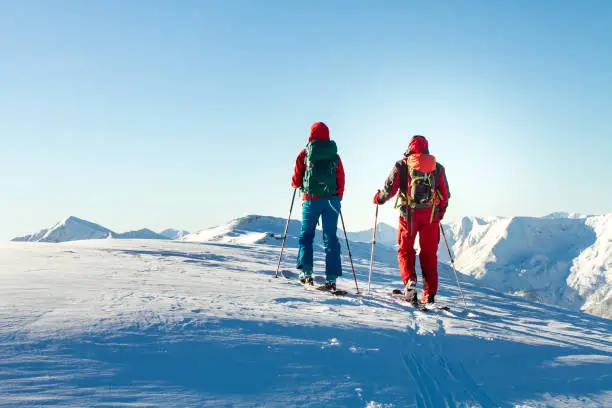 Man and woman ski tourer enjoying the view on a summit in the alps
