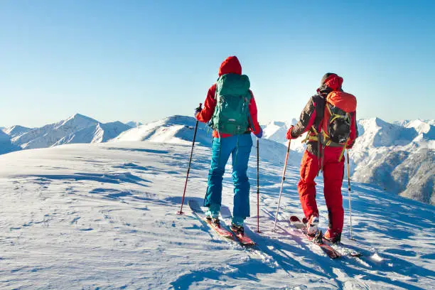Man and woman ski tourer enjoying the view on a summit in the alps