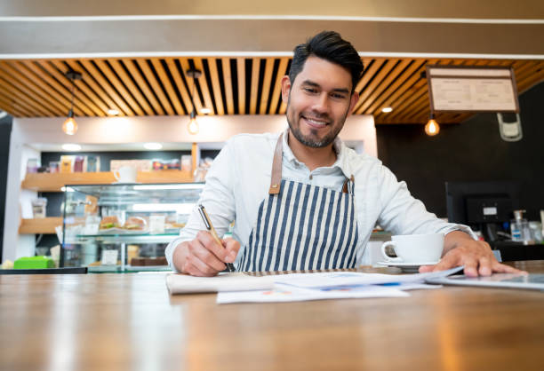 istock Happy business owner of a bakery doing the books using documents and tablet smiling 1128048545