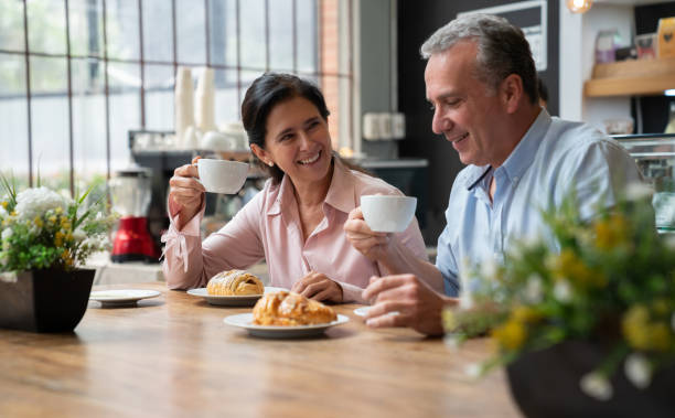 istock Mature couple at a bakery on a date eating pastry desserts and a coffee while talking and smiling 1128048608