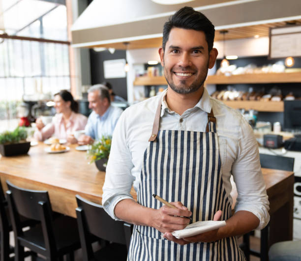 istock Successful business owner of a cafeteria holding a notepad while looking at camera smiling 1128048615