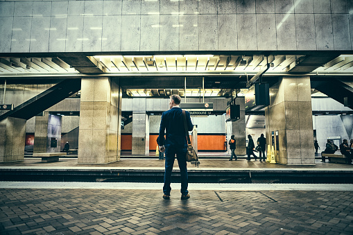 Businessman stands by train platform