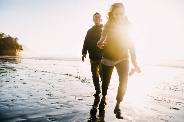 amorevole coppia matura che gioca sulla costa dell'oregon - couple romance running freedom foto e immagini stock