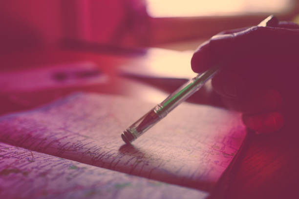 Male hand selects a place on the map using the pen. Dark image with selective light. Violet tone