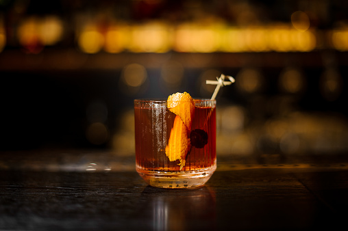 Glass of a Old Fashioned cocktail on the wooden bar counter