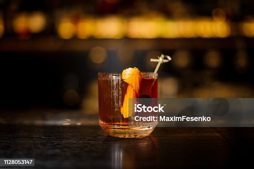 istock Glass of a Old Fashioned cocktail on the wooden bar counter 1128053147
