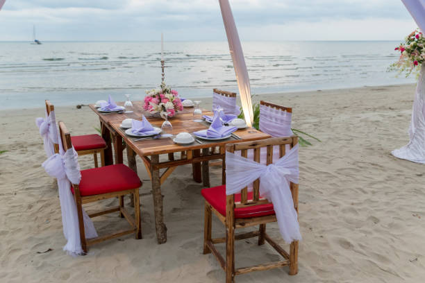 istock Romantic dinning table on the beach . Table setting at a luxury wedding and Beautiful flowers on the table. 1128053346