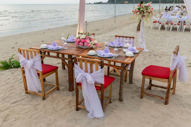 istock Romantic dinning table on the beach . Table setting at a luxury wedding and Beautiful flowers on the table. 1128053352