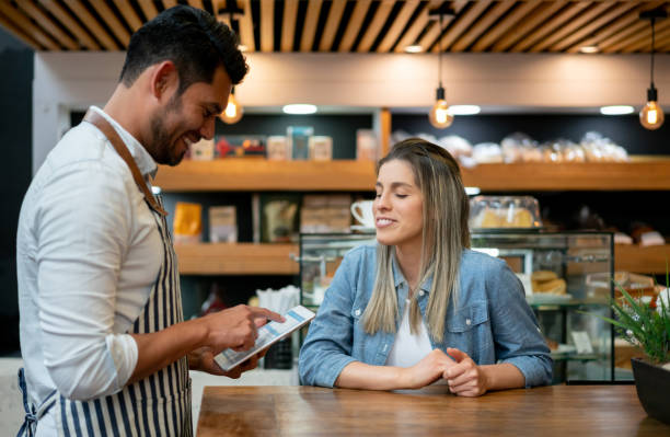 istock Handsome waiter taking an order from female customer on tablet both smiling 1128053636